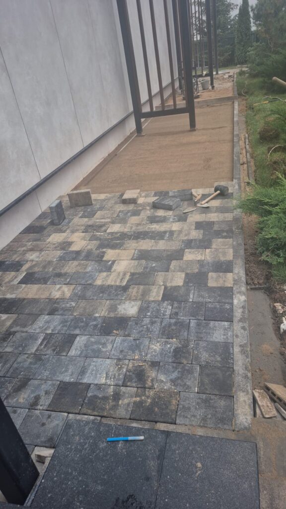 Narrow paved side access between a wall and boundary fence
