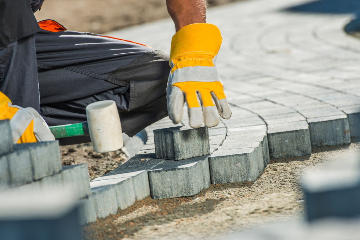 Worker setting paving edge blocks with a rubber mallet