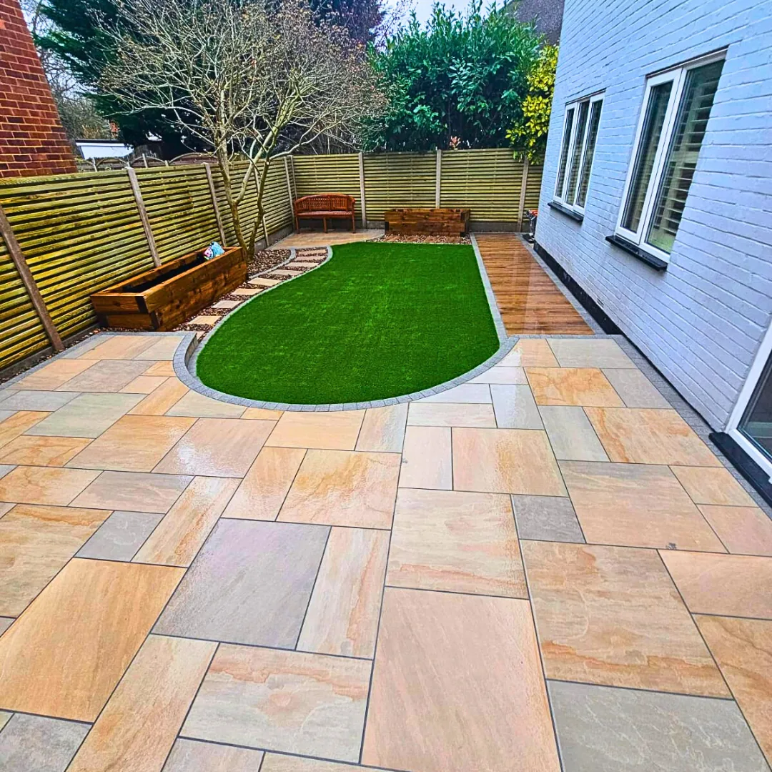 Completed sandstone patio with a curved lawn and raised planting beds