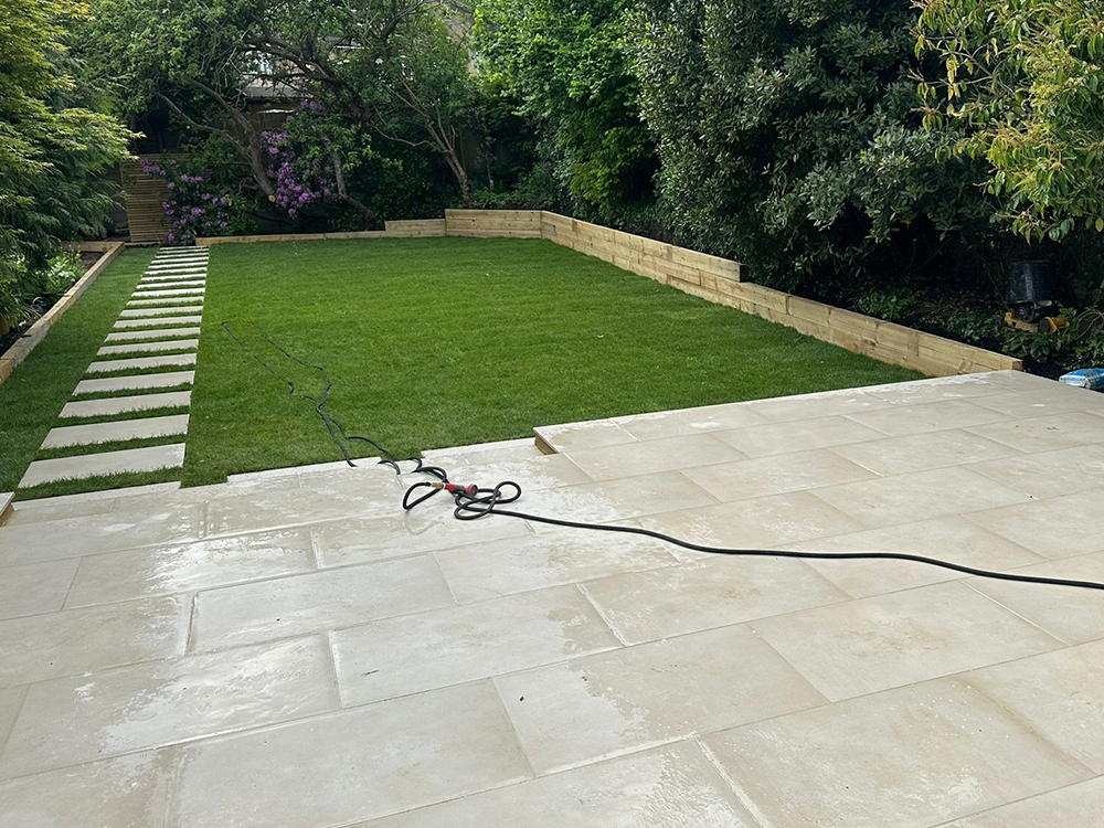 After: Finished paved terrace beside a lawn and raised beds